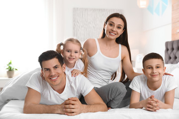 Happy young family together on large bed