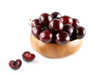 Cherries in a wooden cup on a white isolated background. Two half cherry lie on a white background