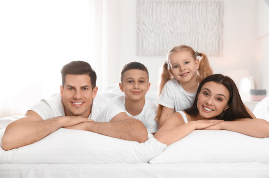 Portrait of happy family on large bed in room