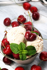 Cherry and vanilla ice cream scoop with fresh cherries and mint on a rustic background