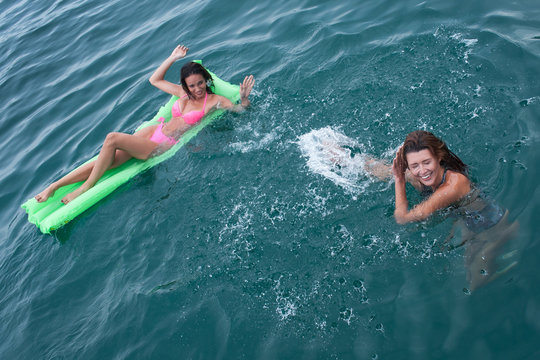 ragazze in vacanza che si divertono facendo il bagno in mare giocando con un materassino