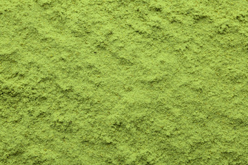 Green wheat grass powder as background, top view