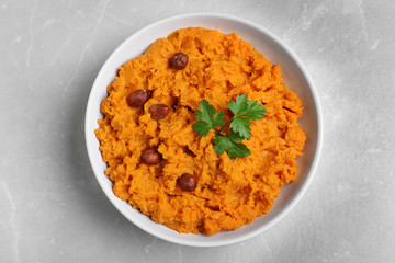 Bowl of tasty sweet potato puree on grey marble table, top view