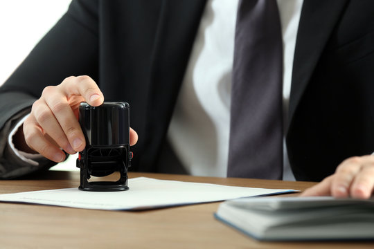 Male notary stamping document at table, closeup