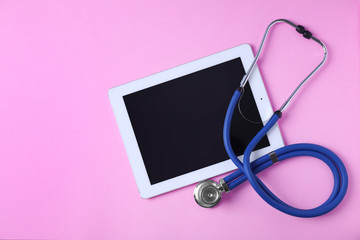 Flat lay composition with tablet and stethoscope on pink background, space for text. Gynecology concept