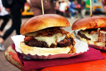 Organic Burger on street food festival in hand. Pulled pork or burger are sold on Open kitchen food festival event. Street food