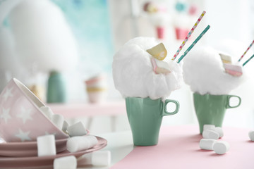 Cups of tasty cotton candy dessert and marshmallow on table, space for text