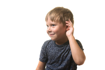 Little boy listens with a hand to his ear isolated on white background.