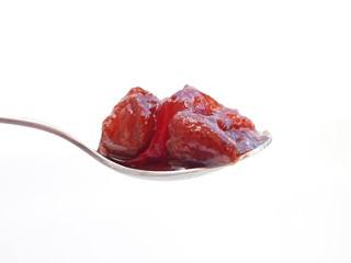 close up of straeberry jam spoon over white background