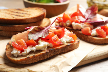 Serving board with tasty bruschettas on table, closeup