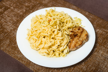 Meat roast cutlet with boiled pasta, spaghetti on a brown background. Simple fast food.