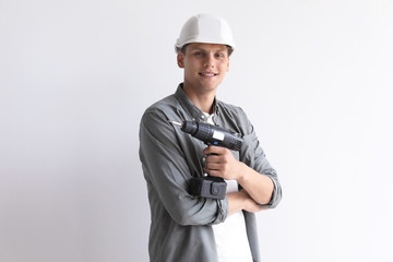 Young working man with electric screwdriver on white background