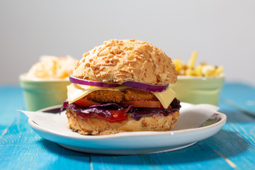 Delicious homemade burger with french fries and salad (coul slow) on a blue table and neutral grey background