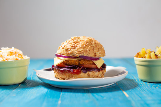 Delicious homemade burger with french fries and salad (coul slow) on a blue table and neutral grey background