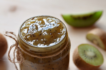Top view kiwi jam jar with raw fruit wooden table background