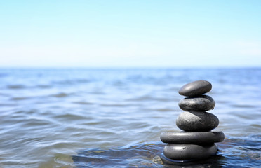 Stack of stones in sea water, space for text. Zen concept