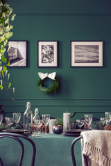 Real photo of an elegant dining room interior prepared for a family Christmas celebration. Plates and glasses on a green cloth.