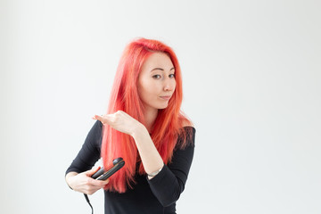 Hair Stylist, hairdresser and people concept - young woman with colored hair holding curling iron over white background