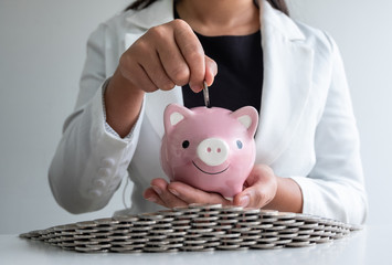 woman hand putting coin into pink piggy bank saving money with coins bunker, step up protect...