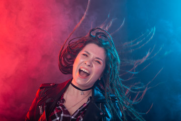 Youth, hairstyle and modern concept - young woman with dreadlocks smiling and having fun over the red and blue light background