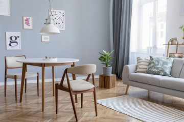 Design scandinavian home interior of open space with stylish chairs, family table wooden commode,...