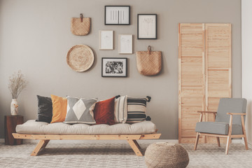 Red, yellow and patterned pillows on elegant scandinavian living room sofa