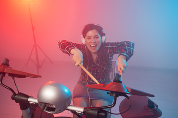 Music, drum and hobby concept - young woman playing the electronic drum set at the club