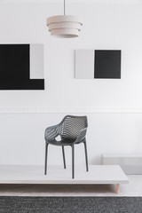 Fashionable grey metal chair on white platform in fancy showroom