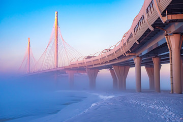 Modern highway. Highway on stilts. Route on a foggy winter morning. Expressway. City road junction. The architecture of the bridges. Road viaduct.