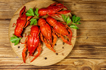 Boiled crayfish on cutting board on wooden table. Top view