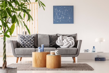 Trendy knot light grey pillow on comfortable scandinavian couch
