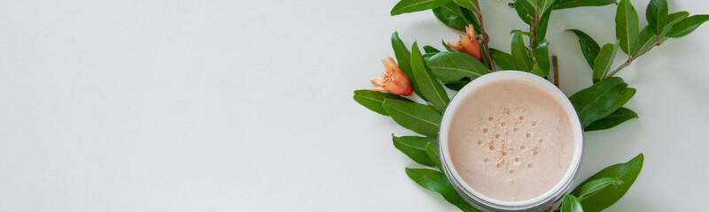 Top view of botanical face powder with blossom pomegranate branch. Herbal cosmetics