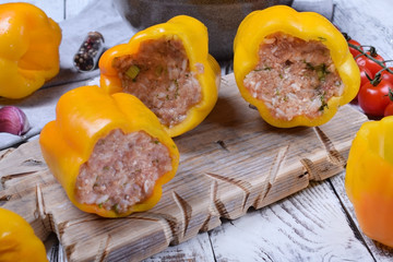 Yellow bell peppers stuffed with raw pork and beef mince on the board. Process of making a meal