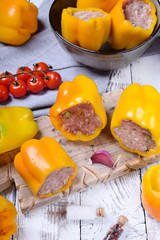 Yellow bell peppers stuffed with raw pork and beef mince on the board. Process of making a meal