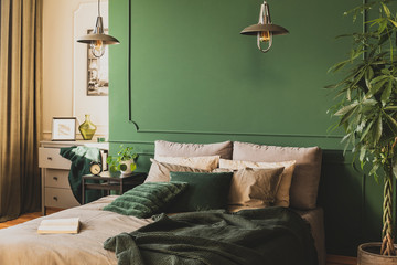 Two industrial lamps above comfortable double bed with cozy bedding, copy space on empty wall