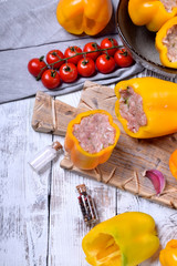 Yellow bell peppers stuffed with raw pork and beef mince on the board. Process of making a meal
