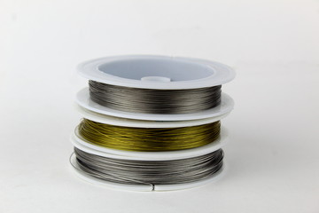 Colored wire for making jewelry from natural stones and natural materials. Wire on white plastic coils.