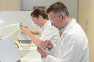 male and female technicians working in opticians laboratory