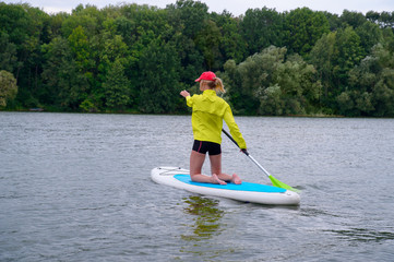 woman is kneeling on a surfboard and holding a paddle. Rear view photo