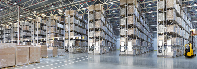 Huge distribution warehouse with high shelves and forklift with driver.