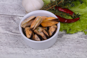 Pickled mussels in the bowl served pepper, garlic and salad