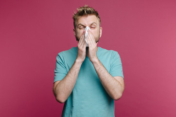 studio picture from a young man with handkerchief. Sick guy isolated has runny nose. man makes a...