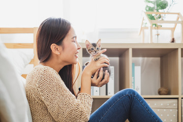 Young Asian woman holding and playing with her cute kitten cat with lovely moment, pet and human...