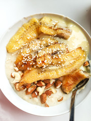Breakfast oatmeal porridge with chia seeds, nuts, sesame, soy yogurt and banana with a metal spoon. Proper vegetarian breakfast instagram style top view
