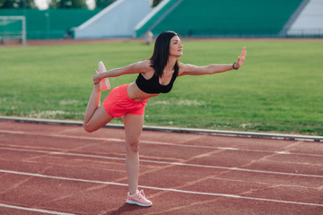Fototapeta na wymiar Young brunette woman athlete in pink shorts and top on stadium sporty lifestyle standing stretching leg side view