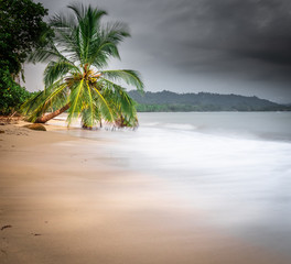 Costa Rica tropical beach at Cahuita National Park at rainy season. Photo taken at slow shutter speed, making smooth waves. 