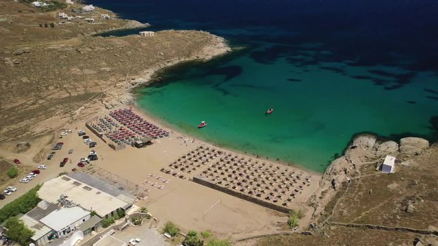Aerial drone video of famous organised with sun beds and umbrellas beach of Lia with emerald clear sandy sea shore, Mykonos island, Cyclades, Greece  