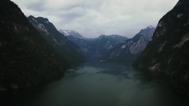Aerial dark cinematic shot of the Konigsee lake in Bavarian Alps, Germany before the storm. Flashes of lightning on the horizon