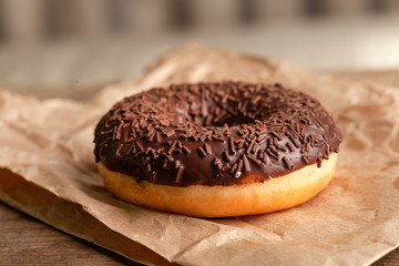 Chocolate-coated doughnut and chocolate sprinkles close-up. On parchment
