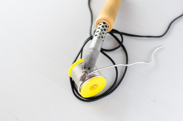 solder wire and soldering iron with wooden handle on gray background